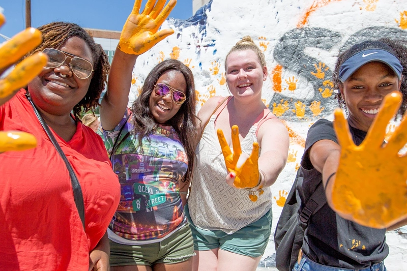 students with orange paint on their hands putting hand prints on "the rock" at The University of Tennessee