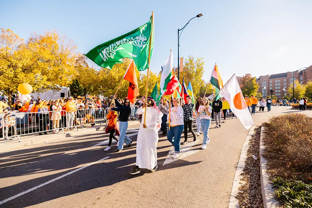 International students carry flags while walking together in the homecoming parade on November 03, 2023.