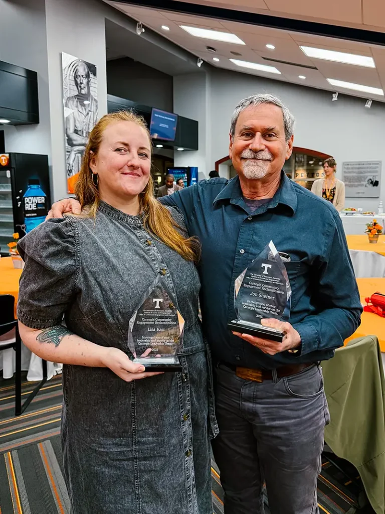 Lisa East and Jon Shefner hold awards.